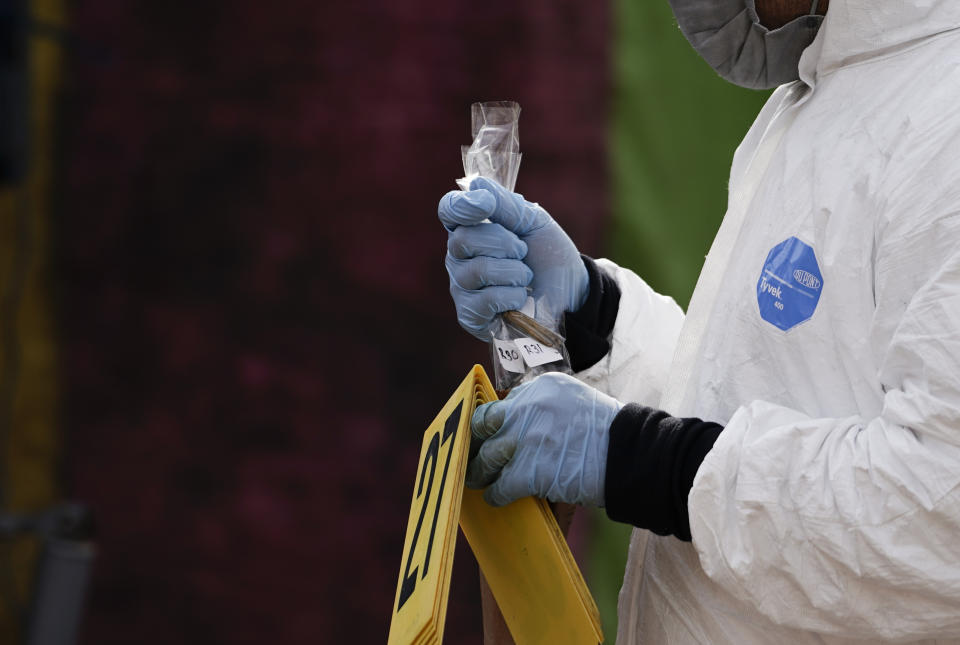 A forensics investigator works the scene of a massive shootout in San Miguel Totolapan, Mexico, Thursday, Oct. 6, 2022. A drug gang burst into the town hall and shot to death 20 people, including a mayor and his father, officials said Thursday. (AP Photo/Eduardo Verdugo)