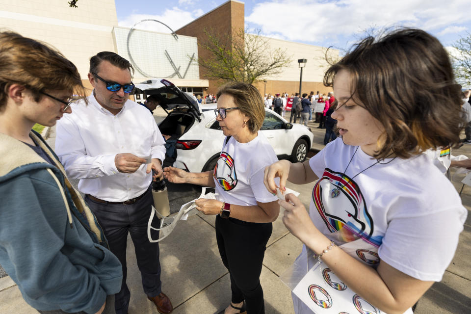 Brooke Ryerson, 16, right a 10th grade student and her mom Valarie Ryerson of Hampden Twp., Pa., hand out stickers with the eagle logo on a rainbow background before the the Cumberland Valley School Board holds a special meeting to discuss their decision to cancel an assembly featuring "30 Rock" star, Maulik Pancholy, Wednesday, April 24, 2024. (Joe Hermitt/The Patriot-News via AP)