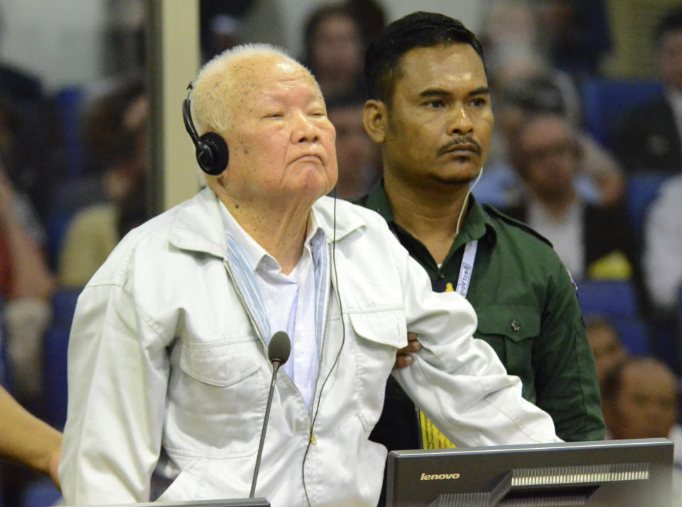 In this photo released by the Extraordinary Chambers in the Courts of Cambodia, Khieu Samphan, left, former Khmer Rouge head of state, stands at the dock in a court room during a hearing at the U.N.-backed war crimes tribunal in Phnom Penh, Cambodia, Friday, Nov. 16, 2018. A U.N.-backed tribunal in Cambodia on Friday convicted the two most senior surviving leaders of the country's former Khmer Rouge regime of genocide and other crimes against humanity, sentencing them to life in prison. (Nhet Sok Heng/Extraordinary Chambers in the Courts of Cambodia via AP)