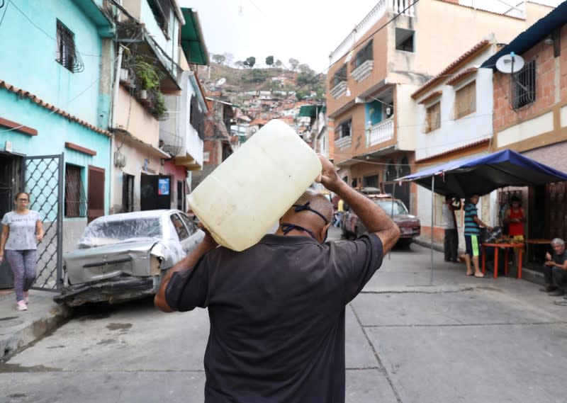 A man carries a plastic container with water in the low-income neighbourhood of El Guarataro amid the coronavirus disease (COVID-19) outbreak in Caracas