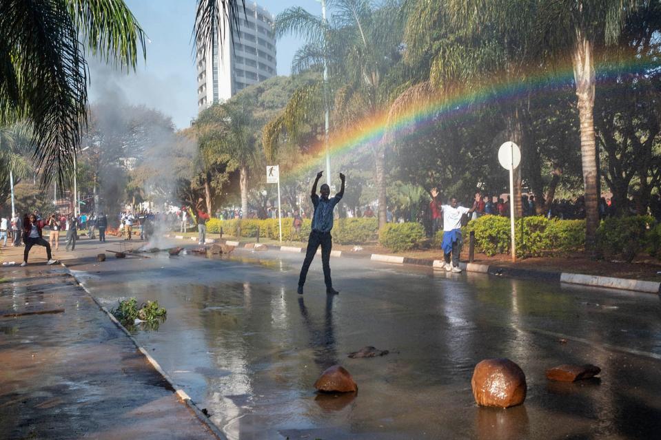 <p>A protester gestures toward police water cannons outside of the gates of the ZImbabwe Electoral Commission (ZEC) during a protest against polling results in Harare, Zimbabwe on 1 August 2018. The day saw protests turn violent when police fired rubber bullets and teargas, before the army was called in and began firing live rounds. (Photo: Yeshiel Panchia/EPA-EFE/REX/Shutterstock) </p>