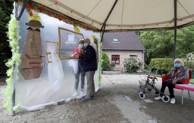 Residents at Belgian nursing home "Le Jardin de Picardie" enjoy hugs and cuddle through a wall made with plastic sheets to protect against potential COVID-19 infection in Peruwelz