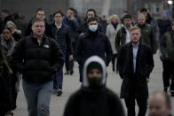 Workers walk over London Bridge towards the City of London financial district during the morning rush hour, in London, Monday, Jan. 24, 2022. The British government have asked people to return to working in offices starting Monday as they ease coronavirus restrictions. (AP Photo/Matt Dunham)