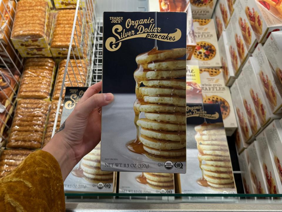 hand holding up a box of frozen silver dollar pancakes at trader joes