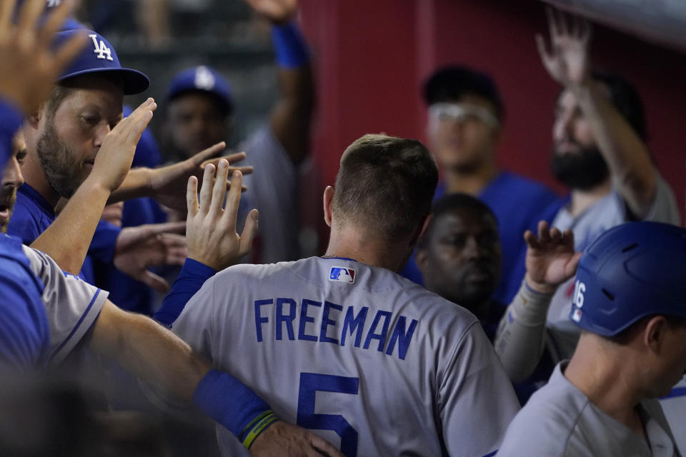 Los Angeles Dodgers' Freddie Freeman (5) is greeted in the dugout after scoring on a sacrifice fly hit by teammate Will Smith during the fifth inning of a baseball game against the Arizona Diamondbacks, Saturday, May 28, 2022, in Phoenix.(AP Photo/Matt York)