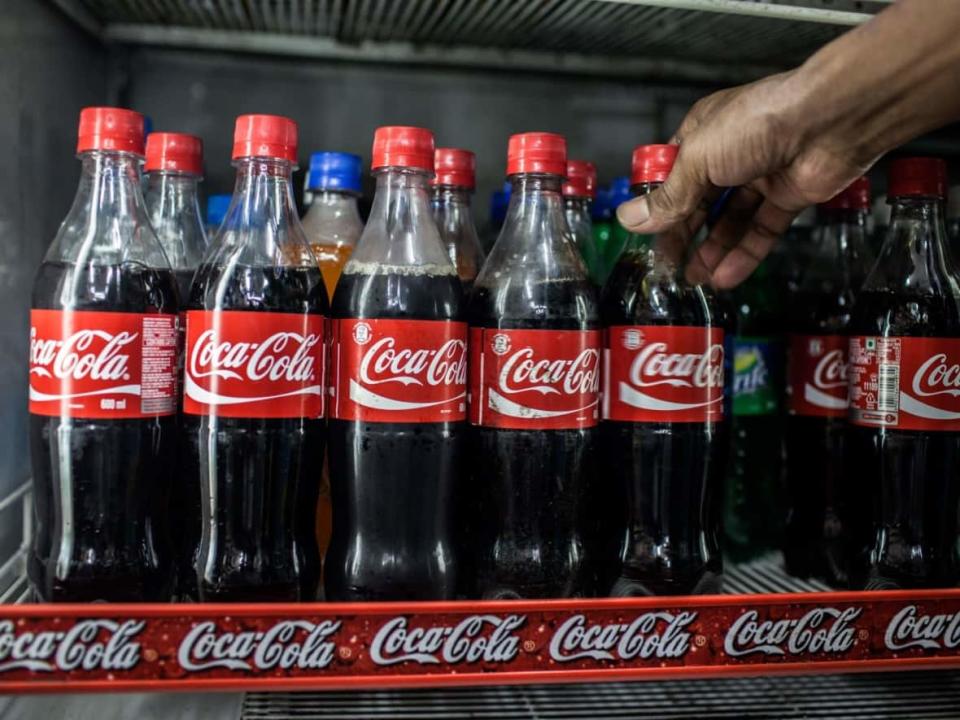 A man grabs a bottle of Coke from a refrigerated display case. Revenues at major snack brands such as Coke, Pepsi, Hershey and others are all up of late, as brands have been able to pass on higher prices to consumers even as demand has remained relatively flat. (Sanjit Das/Bloomberg - image credit)