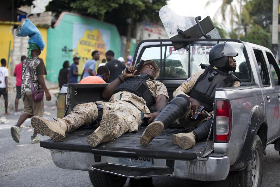 Police officers ride in the back of a pick-up truck with their weapons drawn during a protest to demand the resignation of Haiti's president Jovenel Moise on the 216th anniversary of Battle of Vertieres in Port-au-Prince, Haiti, Monday, Nov. 18, 2019. At least four people were shot and wounded during a small protest in Haiti’s capital after a speech by embattled President Moise. A local journalist, a police officer and two protesters were rushed away with apparent bullet wounds. (AP Photo/Dieu Nalio Chery)