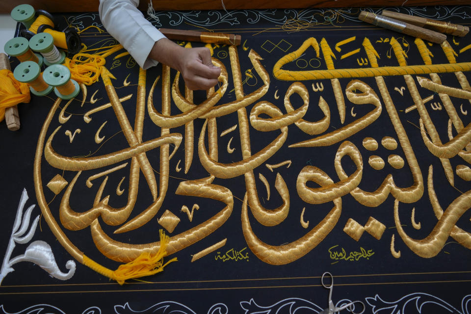 A Saudi man embroiders Islamic calligraphy, using either pure silver threads or silver threads plated with gold, during the final stages in the preparation of a drape, or Kiswa, that covers the Kaaba, a cube-shaped structure at the heart the Grand Mosque, at the Kiswa factory in Mecca, Saudi Arabia, Thursday, June 13, 2024. (AP Photo/Rafiq Maqbool)