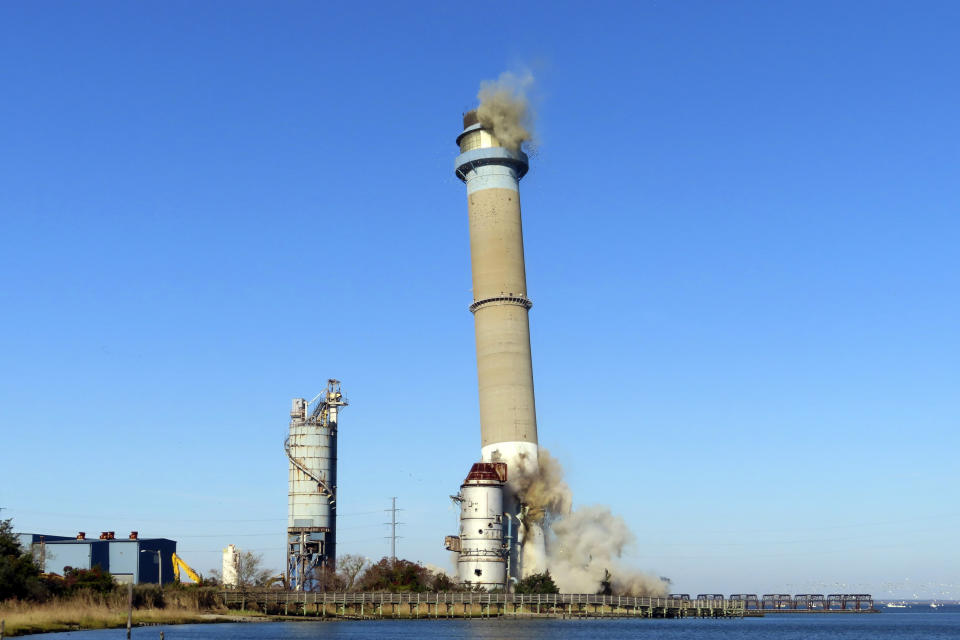 The smokestack at the former B.L. England power plant in Upper Township, N.J., is toppled during a control demolition, Thursday, Oct. 26, 2023. The site will be redeveloped as a mixed use residential and commercial project, and a nearby electrical substation will be used to connect New Jersey's soon-to-come offshore wind farms with the electrical grid. (AP Photo/Wayne Parry)