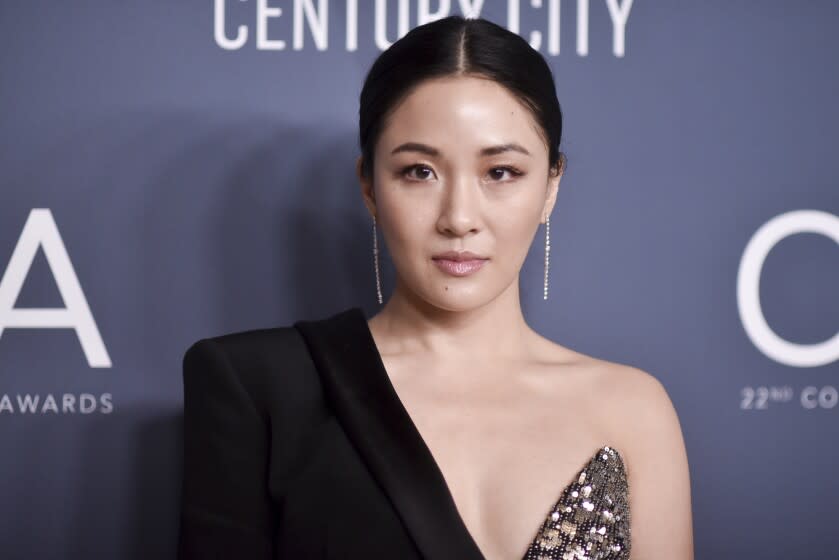 A woman with black hair in a bun wearing a black blazer and sparkly top