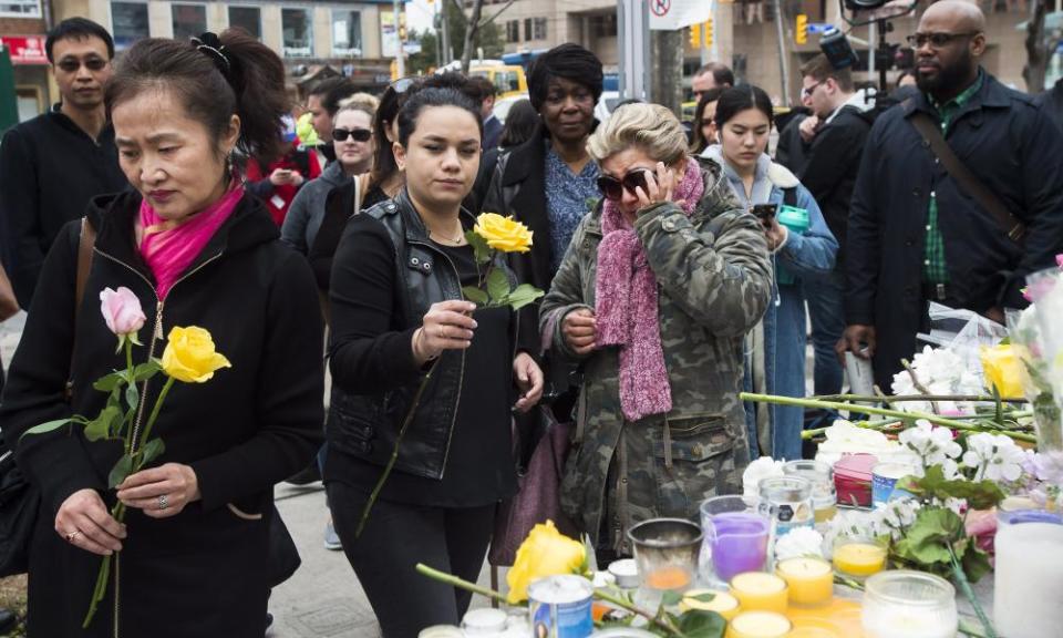 People place flowers at a memorial for the victims of Monday’s van attack in Toronto