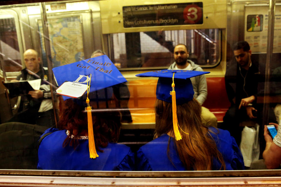 Two graduates sit dressed in caps and gowns on the subway in New York, U.S., May 19, 2016.   REUTERS/Shannon Stapleton