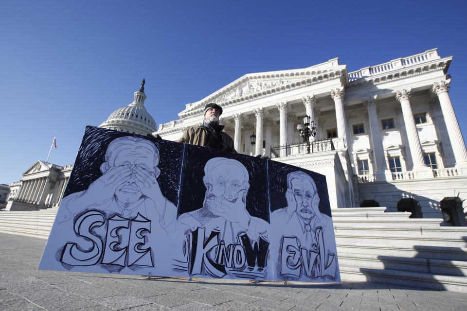 Stephen Parlato, of Bolder, Colo., displays his artwork depicting, "the evil Republican senatorial judges", as he demonstrates outside the U.S. Capitol Wednesday, Jan. 22, 2020, in Washington. (AP Photo/Steve Helber)