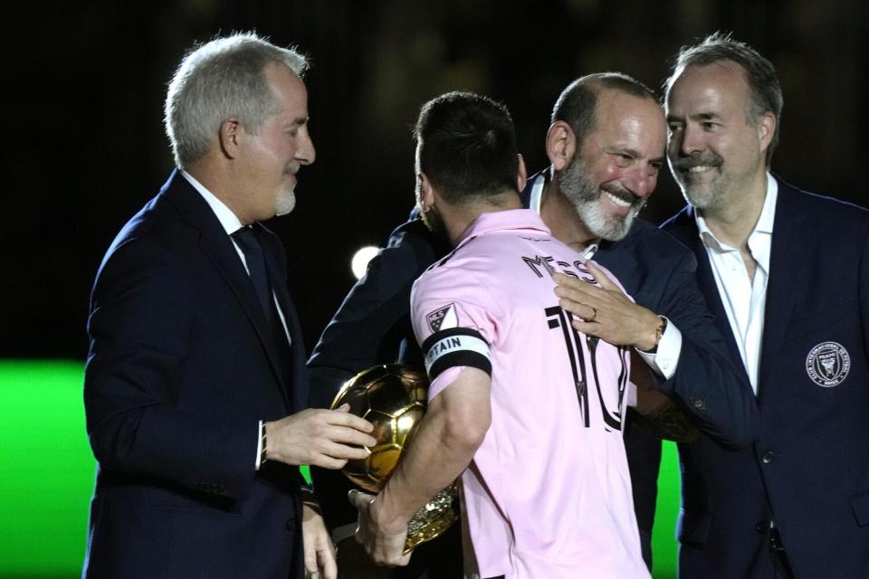 Inter Miami forward Lionel Messi is hugged by MLS commissioner Don Garber, center right.