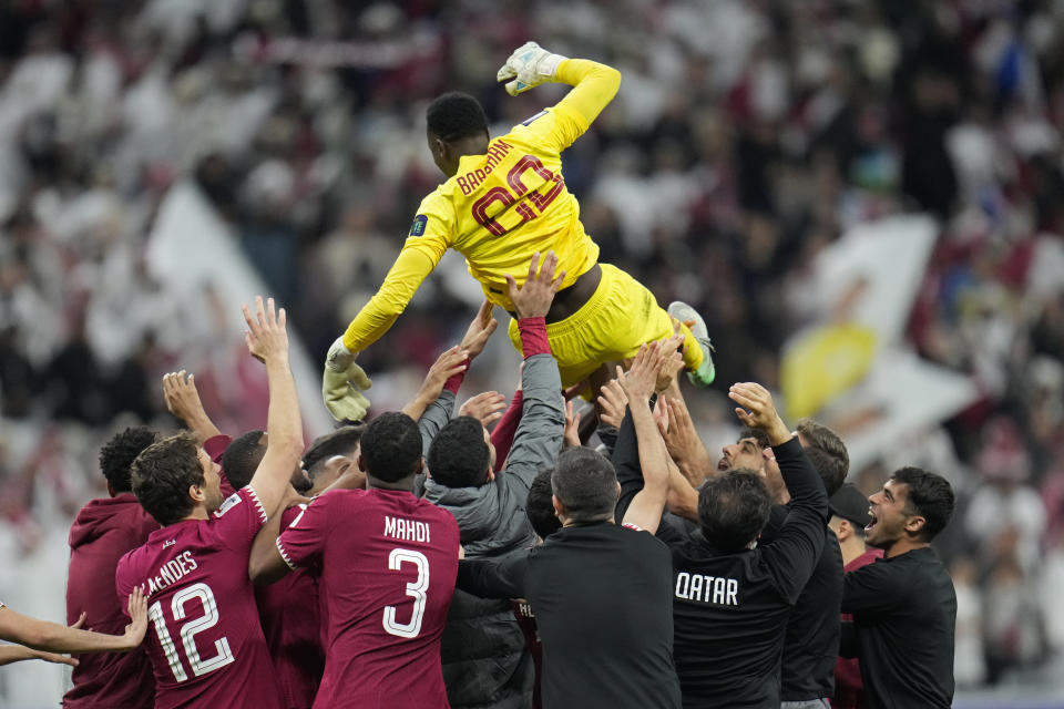 Members of team Qatar throw goalkeeper Meshaal Barsham in air to celebrate their win in the Asian Cup quarterfinal soccer match between Qatar and Uzbekistan at Al Bayt Stadium in Al Khor, Qatar, Saturday, Feb. 3, 2024. (AP Photo/Aijaz Rahi)