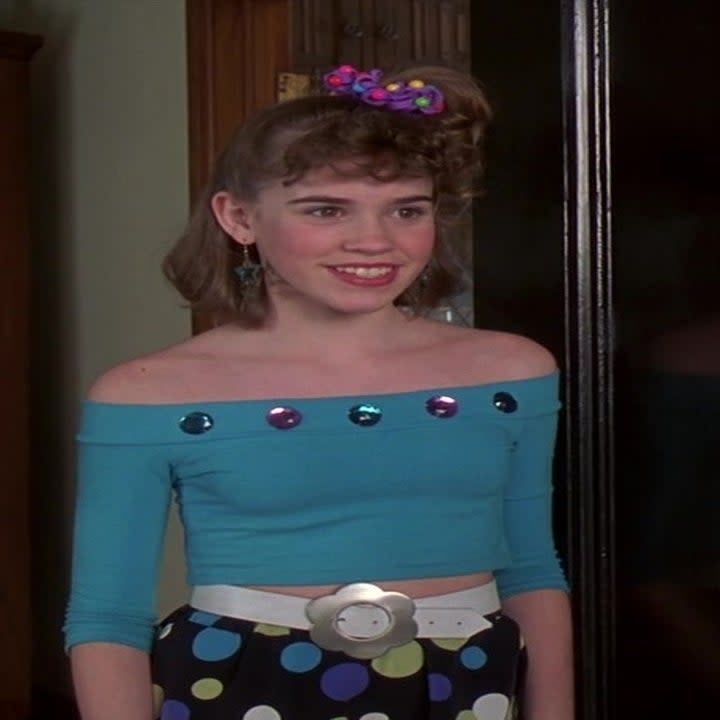 Young Jenna wearing an 80s off-the-shoulder top and a side ponytail