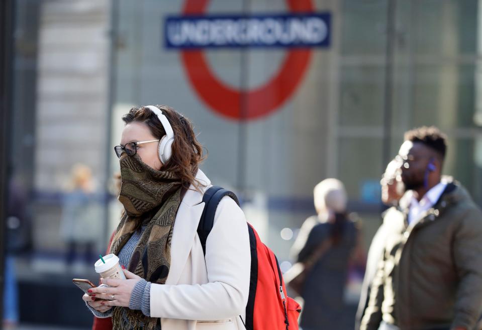 A commuter covers her face in London, Monday, March 16, 2020. For most people, the new coronavirus causes only mild or moderate symptoms, such as fever and cough. For some, especially older adults and people with existing health problems, it can cause more severe illness, including pneumonia. (AP Photo/Kirsty Wigglesworth)