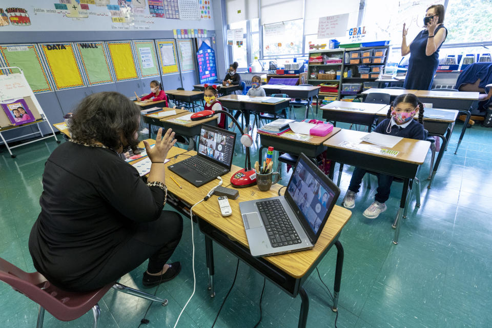 FILE - This file photo from Tuesday, Oct. 20, 2020, shows first-grade teacher Megan Garner-Jones, left, and Principal Cynthia Eisner silent clap for their students participating remotely and in-person at School 16, in Yonkers, N.Y. Teachers unions called Wednesday, Jan. 6, 2021, for New York to shutter schools as the state reverses course on a policy to switch to remote-learning in regions that reach 9% positivity. (AP Photo/Mary Altaffer, File)