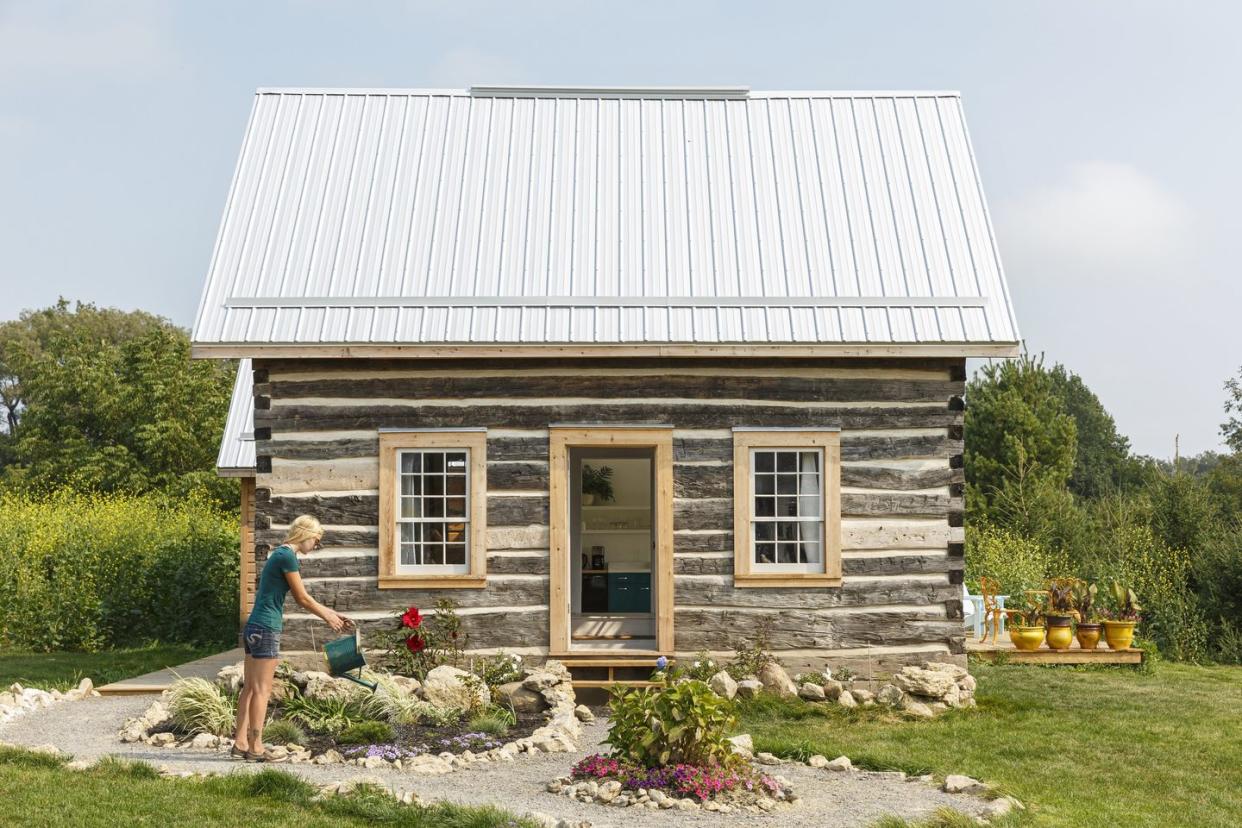 log cabin with person watering flowers