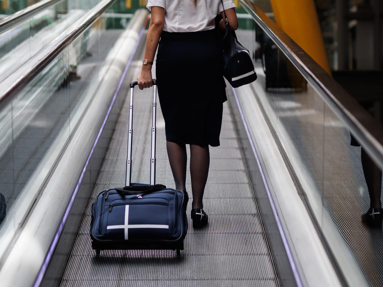 flight attendant riding moving walkway at aiport with suitcase