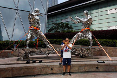 People take a selfie in front of a tightened up sculpture at the financial Central district as Typhoon Mangkhut approaches Hong Kong, China September 15, 2018. REUTRERS/Bobby Yip