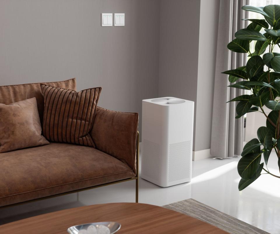 An air purifier by a brown sofa and a coffee table in a lounge