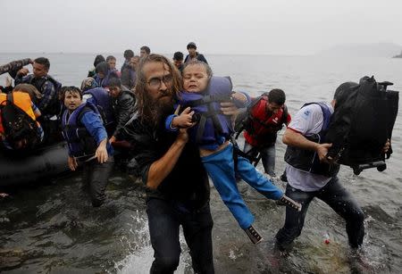 File photograph shows a volunteer carrying a Syrian refugee child off an overcrowded dinghy at a beach after the migrants crossed part of the Aegean Sea from Turkey to the Greek island of Lesbos September 23, 2015. REUTERS/Yannis Behrakis/files