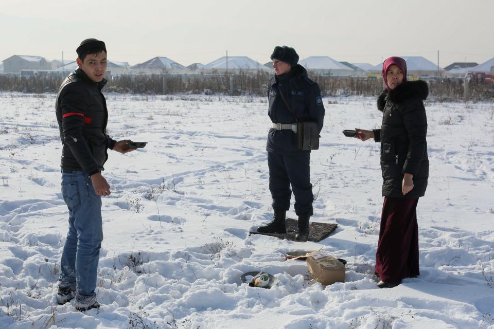 Local residents offer food to a soldier cordoning off the site of a passenger plane crash outside Almaty on December 27, 2019. - At least 15 people died on December 27, 2019 and dozens were injured when a passenger plane carrying 100 people crashed shortly after takeoff from Kazakhstan's largest city and slammed into a house, state media reported. (Photo by Ruslan PRYANIKOV / AFP) (Photo by RUSLAN PRYANIKOV/AFP via Getty Images)