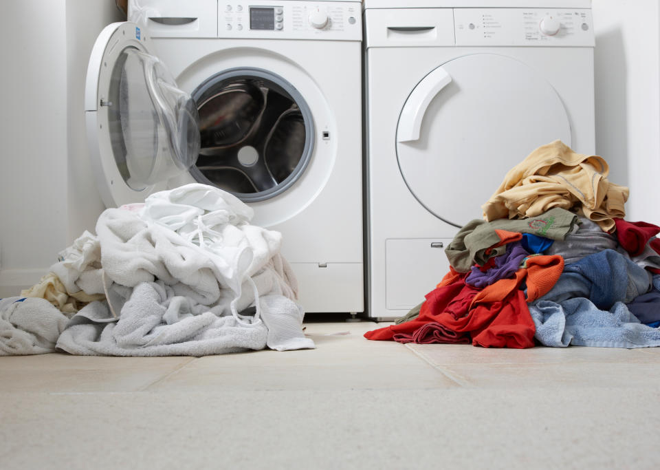 Piles of clothing in front of washing machines 