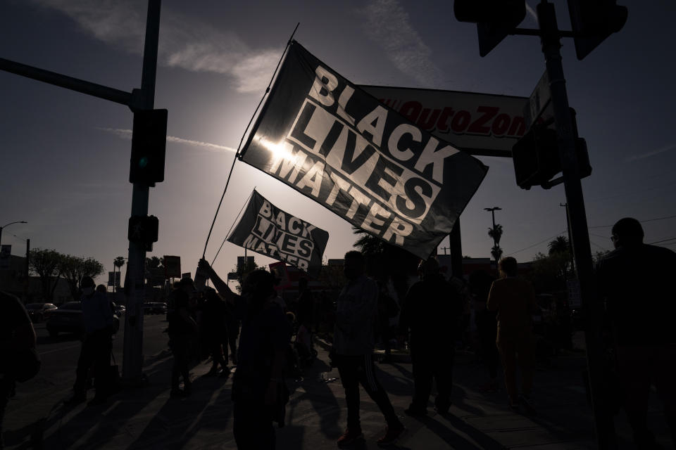 People hold Black Lives Matter flags at the intersection of Florence and Normandie Avenues, Tuesday, April 20, 2021, in Los Angeles, after a guilty verdict was announced at the trial of former Minneapolis police Officer Derek Chauvin for the 2020 death of George Floyd. (AP Photo/Jae C. Hong)