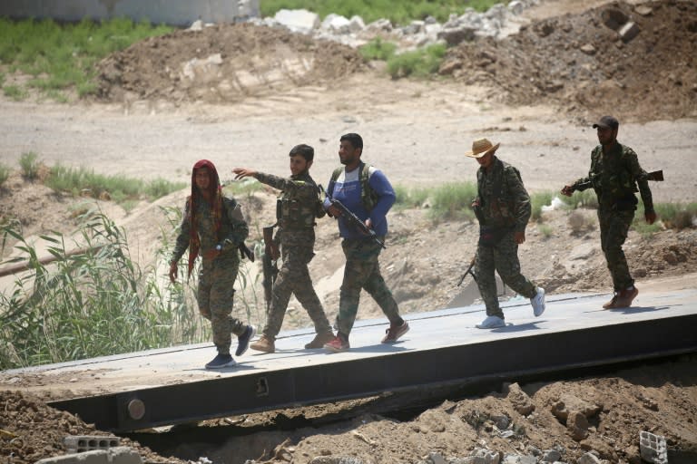 Syrian Democratic Forces fighters cross a bridge after entering the western Raqa on June 11, 2017
