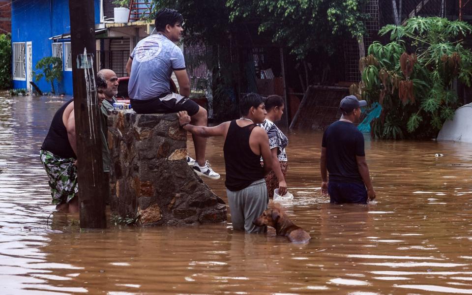 People observe a house damaged by Hurricane John's passage in Acapulco, Mexico, on Thursday