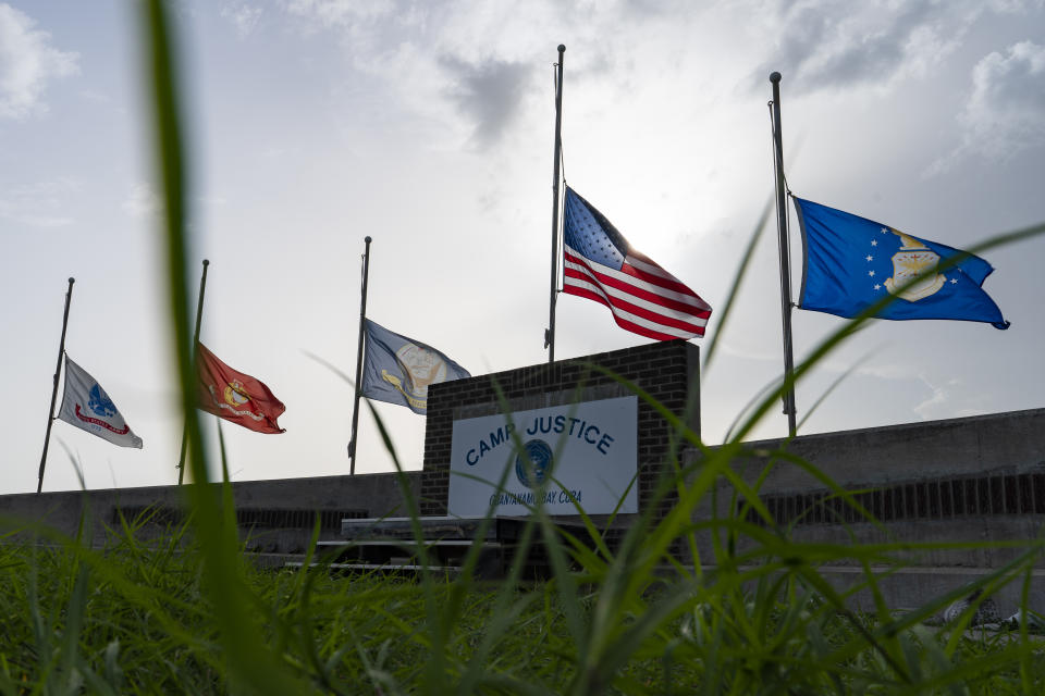 In this photo reviewed by U.S. military officials, flags fly at half-staff in honor of the U.S. service members and other victims killed in the terrorist attack in Kabul, Afghanistan, at Camp Justice, Sunday, Aug. 29, 2021, in Guantanamo Bay Naval Base, Cuba. Camp Justice is where the military commission proceedings are held for detainees charged with war crimes. (AP Photo/Alex Brandon)