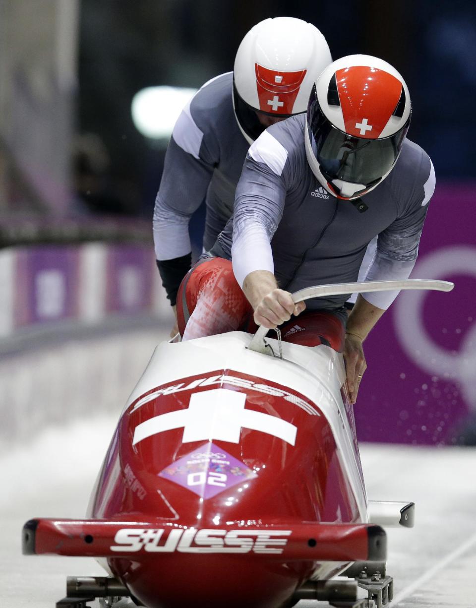 The team from Switzerland SUI-1, piloted by Beat Hefti and brakeman Alex Baumann, start their third run during the men's two-man bobsled competition at the 2014 Winter Olympics, Monday, Feb. 17, 2014, in Krasnaya Polyana, Russia. (AP Photo/Michael Sohn)