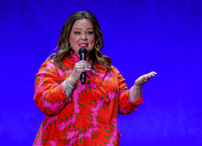 melissa mccarthy holding a microphone and talking to an audience off camera