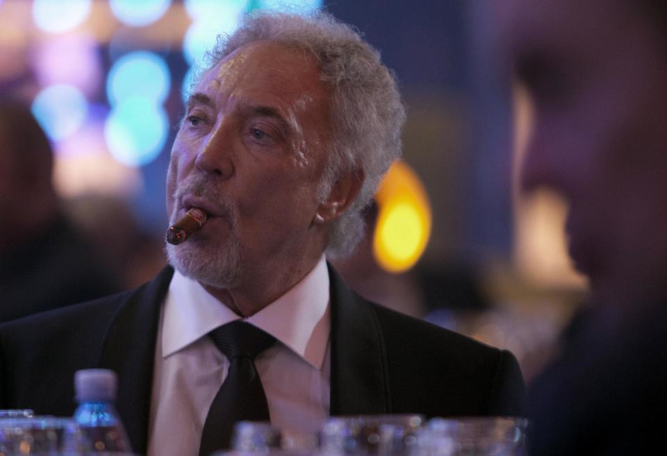 Welsh crooner Tom Jones smokes a cigar during a gala dinner marking the end of the 16th annual Cigar Festival in Havana, Cuba, Friday, Feb. 28, 2014. The festival is a five-day bash that brings together hundreds of cigar sophisticates from around the world, and culminates with a gala and auction of humidors worth hundreds of thousands of dollars. Tom Jones was among the celebrity invitees at Saturday's auction and sang three songs for attending guests, including his signature "It's Not Unusual."(AP Photo/Franklin Reyes)