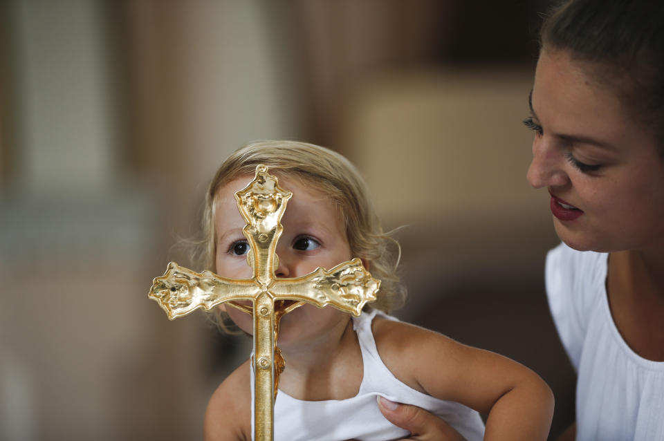 <p>A woman helps a child to kiss a cross, on the altar of a church in the village of Letnica on August 15, 2018, during a mass for Feast of the Black Madonna. – The village owes some of its fame to its connection to Mother Teresa who was a pilgrim in the 1920s at the age of 17, when she is believed to have heard her calling. (Photo by ARMEND NIMANI/AFP/Getty Images) </p>