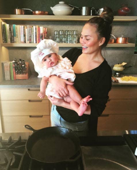 Chrissy Teigen holding her daughter Luna Stephens wearing a fluffy chef's hat