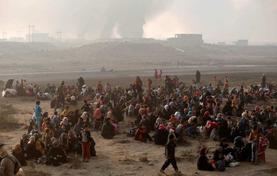 Newly displaced people sit at check point in Qayyara