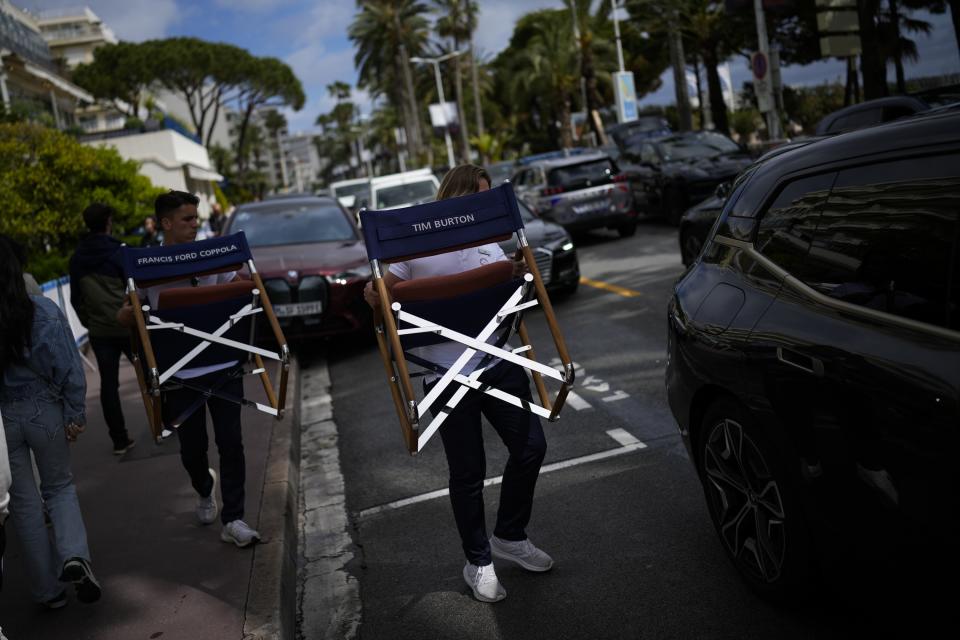 In this May 19, 2023 photo, hotel workers carry beach furniture along the Boulevard de la Croisette during the Cannes Film Festival in Cannes, southern France. (AP Photo/Daniel Cole)