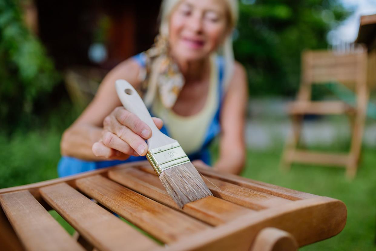 A senior woman cleaning garden furniture and getting the garden ready for summer