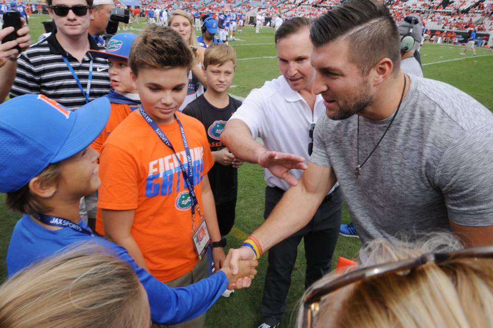 Former University of Florida quarterback Tim Tebow (left) greets the son of Jacksonville Mayor Lenny Curry (center) and one of his son's friends before the 2017 Florida-Georgia game in Jacksonville.