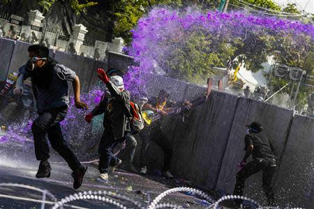 Anti-government protesters flee as riot policemen use water cannon during clashes with the police the metropolitan police headquarters in Bangkok December 2, 2013. REUTERS/Athit Perawongmetha