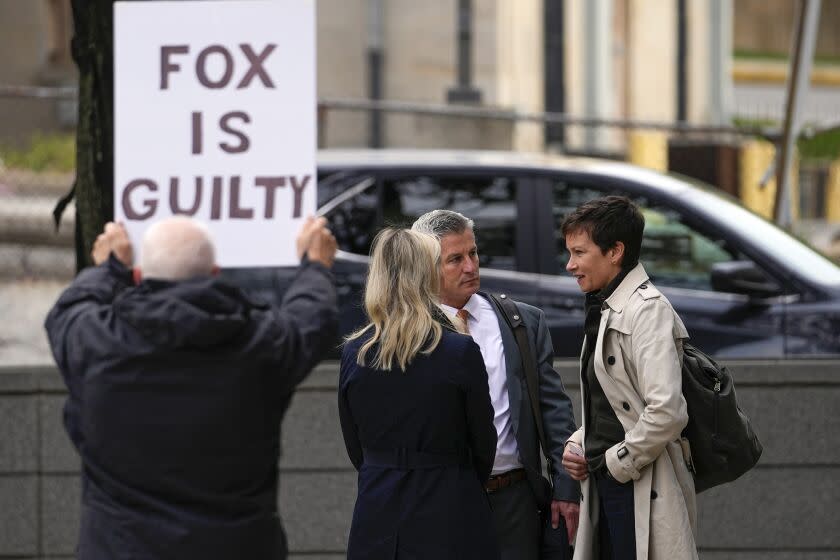 A protester holds a sign near representatives of Fox News outside the justice center for the Dominion Voting Systems' defamation lawsuit against Fox News, Tuesday, April 18, 2023, in Wilmington, Del. (AP Photo/Julio Cortez)