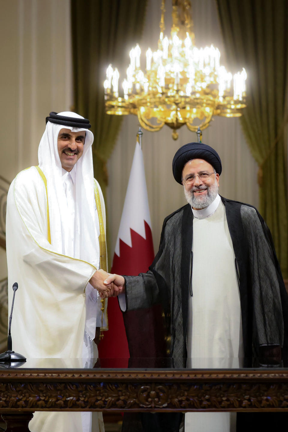 In this photo released by the official website of the office of the Iranian Presidency, President Ebrahim Raisi, right, and Qatari Emir Sheikh Tamim bin Hamad Al Thani shake hands for media during their joint press briefing at the Saadabad Palace in Tehran, Iran, Thursday, May 12, 2022. Qatar's emir arrived in Tehran for talks with the Iranian president as efforts to save Tehran's tattered nuclear deal with world powers hit a deadlock. (Iranian Presidency Office via AP)