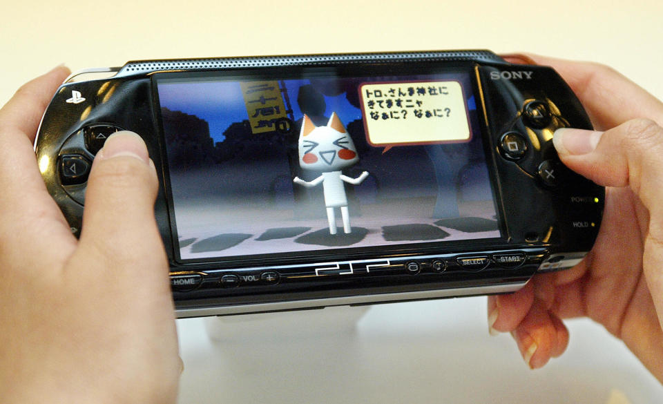 TOKYO, JAPAN:  A journalist tries to play a prototype of Sony's PlayStation Portable (PSP) handheld game console during the PlayStation Meeting 2004 in Tokyo, 12 July 2004. Sony Computer Entertainment will puts the new game console on the Japanese market at the end of 2004 and North American and European markets from Spring of 2005.        AFP PHOTO/Toru YAMANAKA  (Photo credit should read TORU YAMANAKA/AFP via Getty Images)