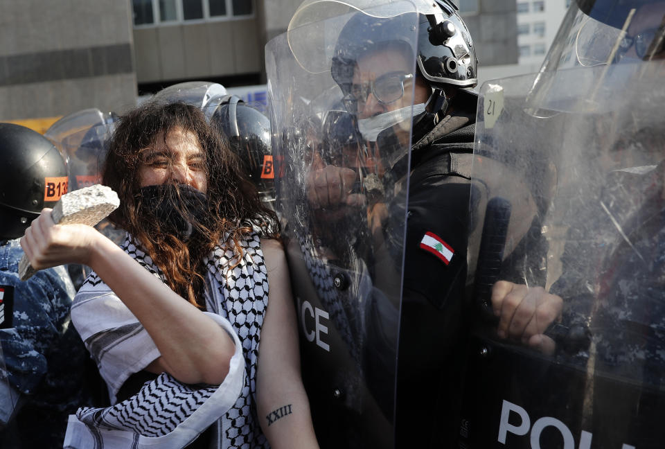 An anti-government protester confronts police with a stone during a protest against the deepening financial crisis, in Beirut, Lebanon, Tuesday, April 28, 2020. Hundreds of protesters set fire to two banks and hurled stones at soldiers, who responded with tear gas and batons in renewed clashes triggered by an economic crisis spiraling out of control amid a weeks-long virus lockdown. (AP Photo/Hussein Malla)