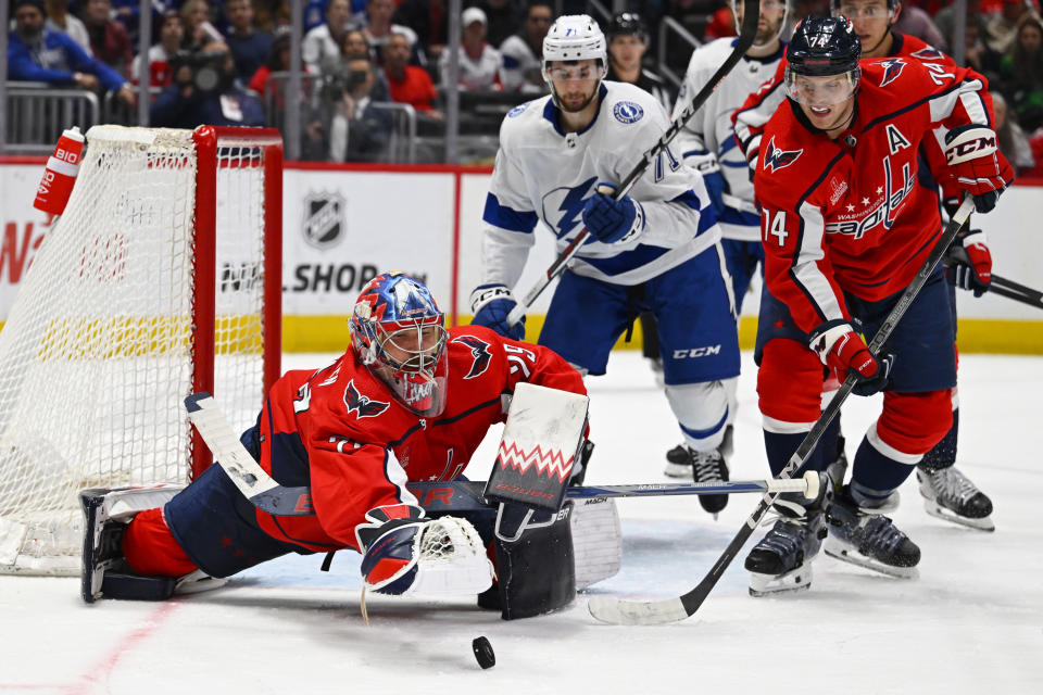 Washington Capitals goaltender Charlie Lindgren, left, makes a diving save in front of Tampa Bay Lightning center Anthony Cirelli (71) and Capitals defenseman John Carlson (74) during the third period of an NHL hockey game Saturday, April 13, 2024, in Washington. (AP Photo/John McDonnell)