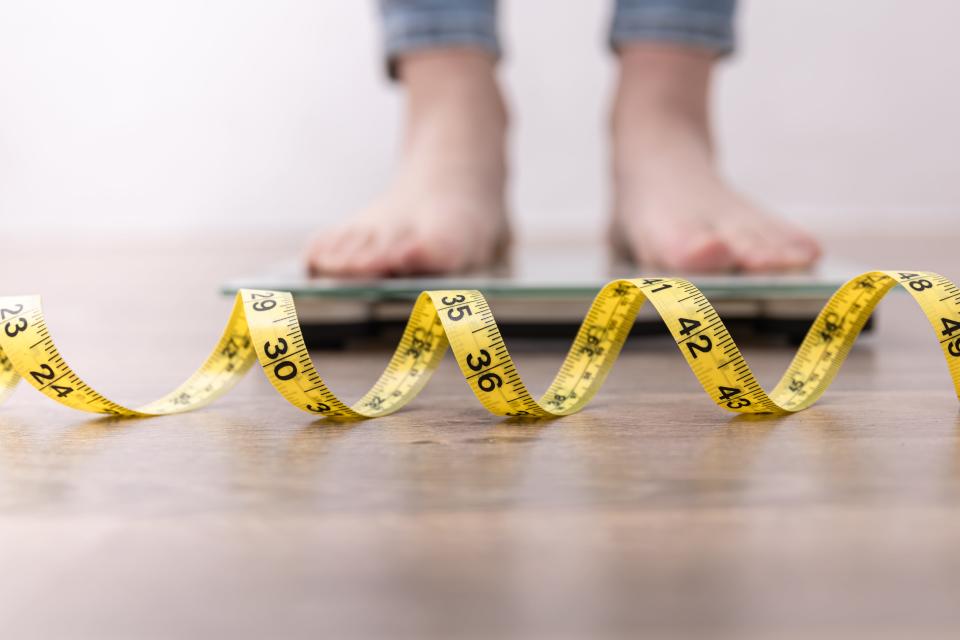 Women's legs on the scales, close-up of a measuring tape, the concept of losing weight, healthy lifestyle.