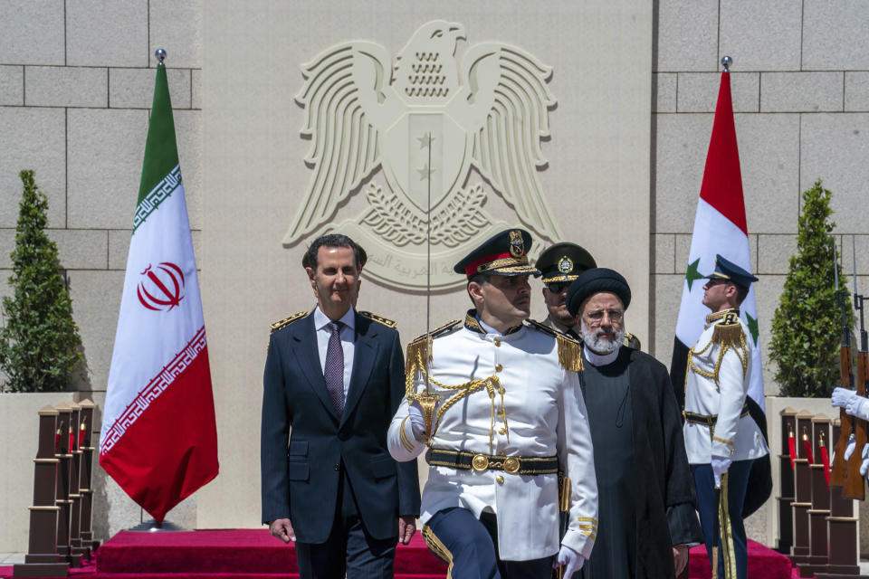 In this photo released by the official Facebook page of the Syrian Presidency, Syrian President Bashar Assad, left, and Iranian President Ebrahim Raisi, second right, review an honor guard during a welcome ceremony upon Raisi's arrival in Damascus, Syria, Wednesday, May 3, 2023. Iranian President Raisi Wednesday met Syrian President Assad in Damascus in a bid to boost cooperation between the two allies, state media reported. (Syrian Presidency via Facebook via AP)